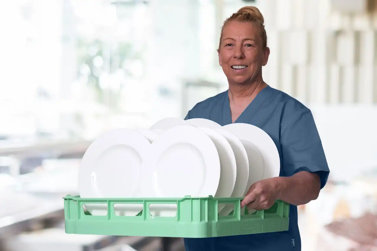 Eine Mitarbeiterin der Gastronomiereinigung in Nürnberg mit einem Spülkorb mit Tellern