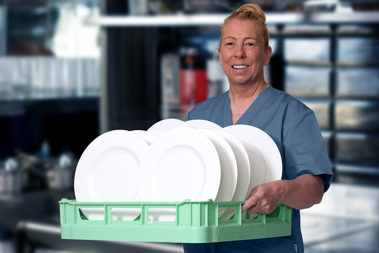 Eine Mitarbeiterin vom Spüldienst in Nürnberg mit einem Spülkorb mit Tellern